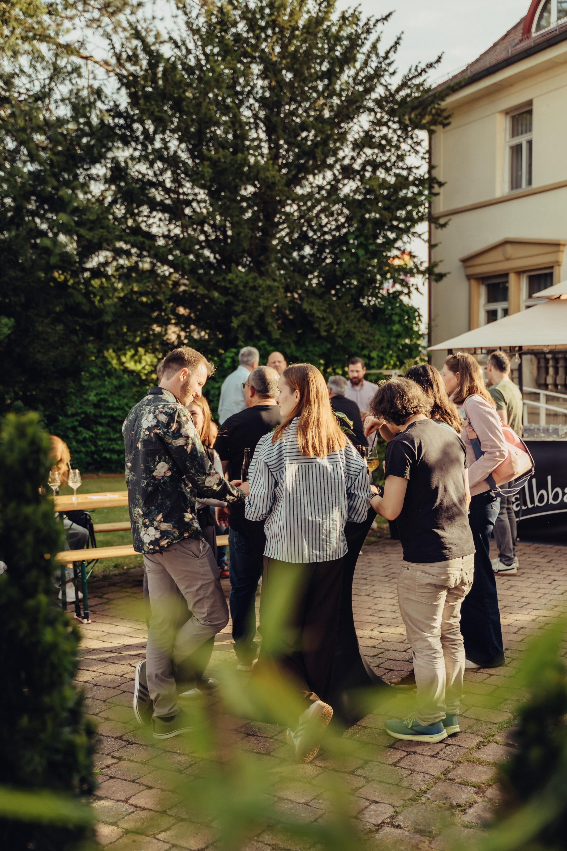 Gäste im Gespräch im Innenhof einer Villa bei Abendlicht